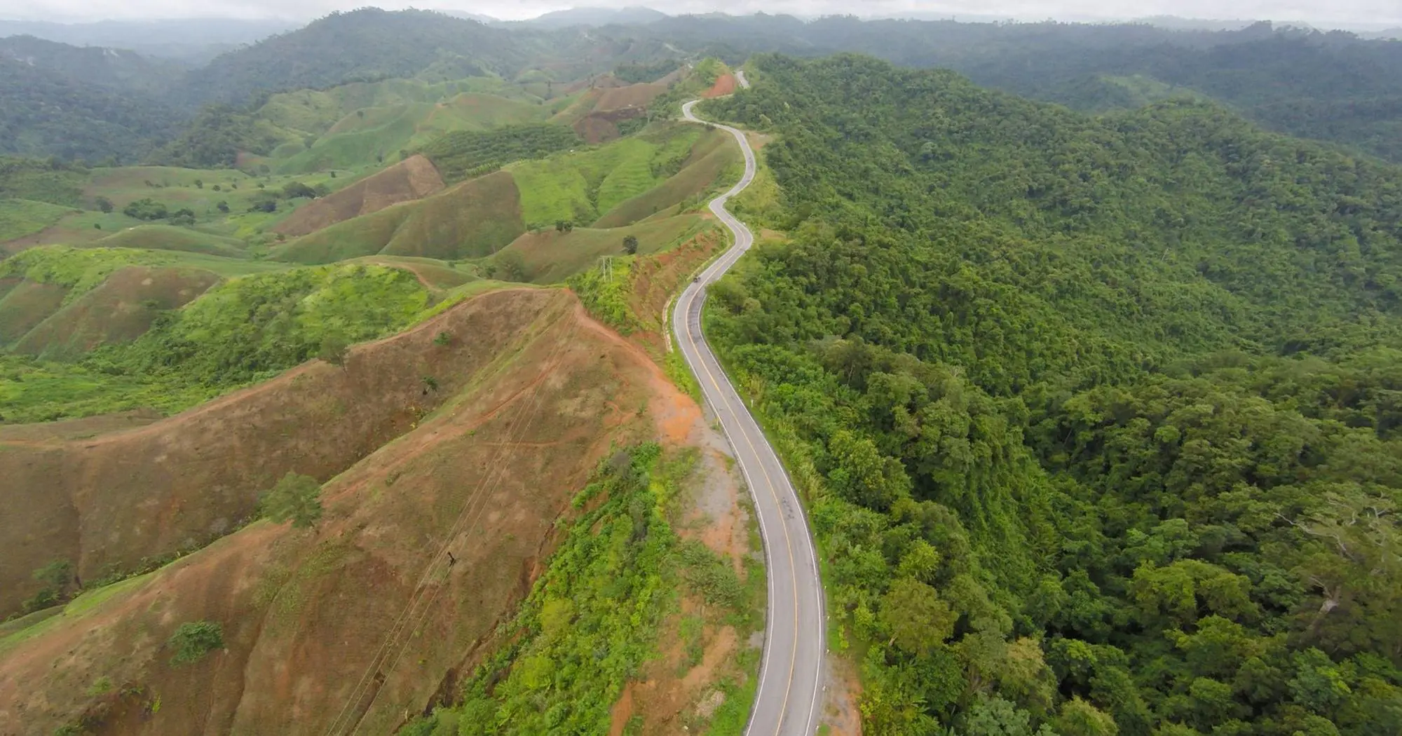 A road curving along a green ridgeline in the mountains of northern Thailand
